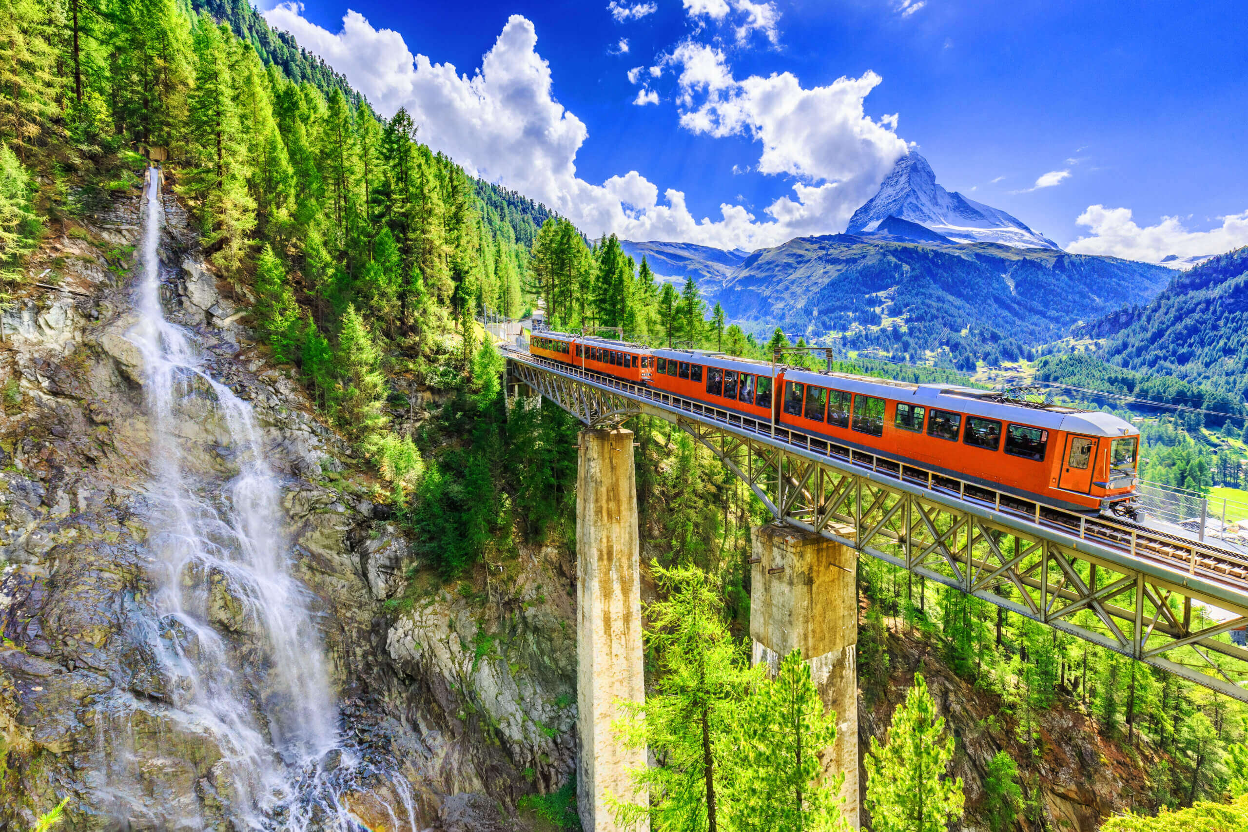 Zermatt,,Switzerland.,Gornergrat,Tourist,Train,With,Waterfall,,Bridge,And,Matterhorn.