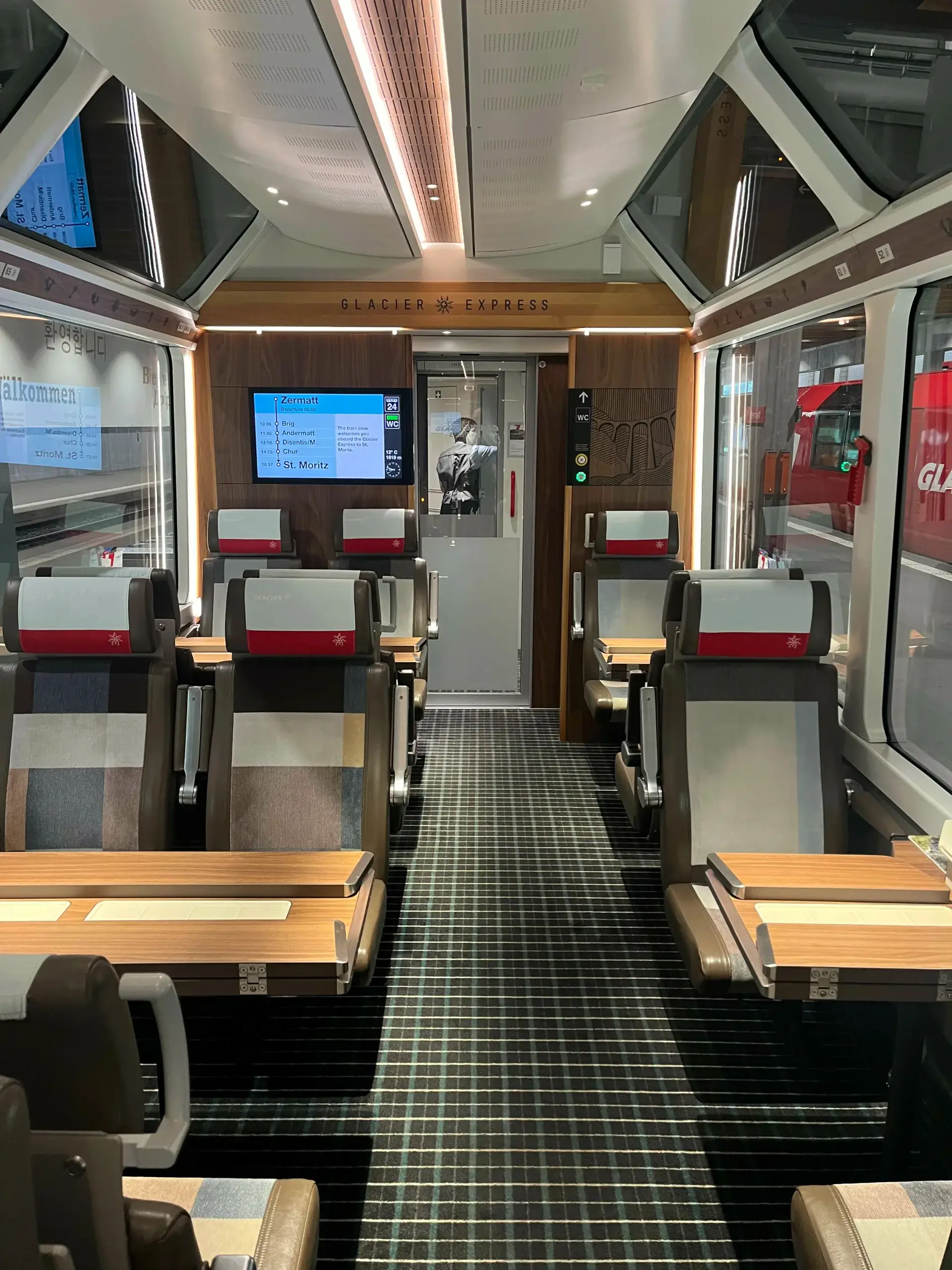 Første klasse i Glacier Express panoramatog med komfortable sæder, store vinduer fra gulv til loft og udsigt til stationen Zermatt.