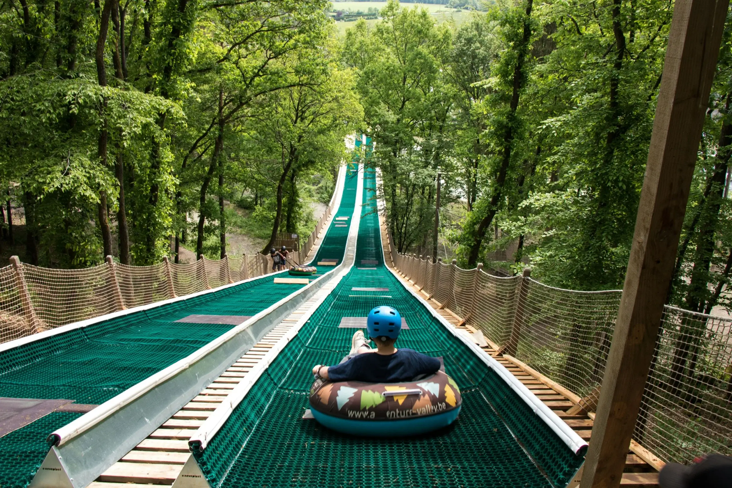 Tubing ned ad en lang grøn bane gennem skoven i Adventure Valley ved Durbuy