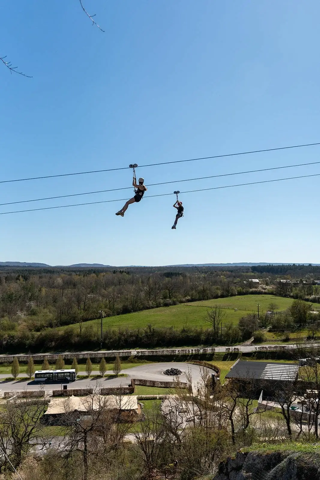 To personer på zipline højt over skovene i Ardennerne ved Adventure Valley Durbuy