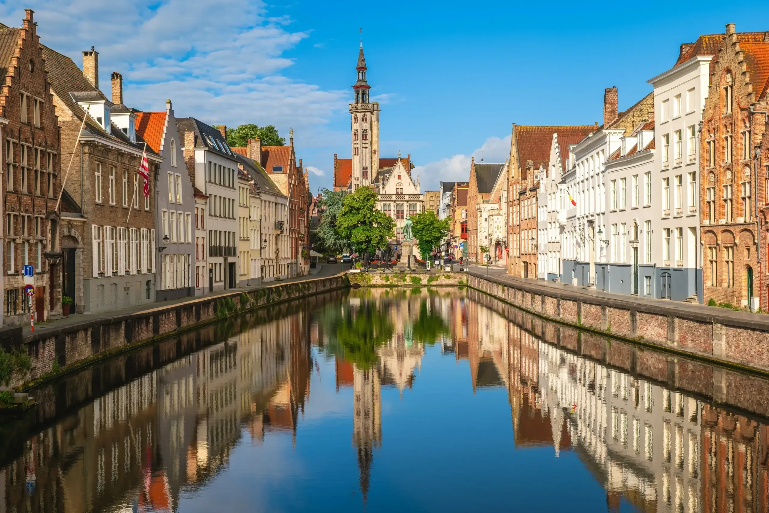 Kanalen Spiegelrei i Brugge med gavlhuse og et tårn der spejler sig i vandet