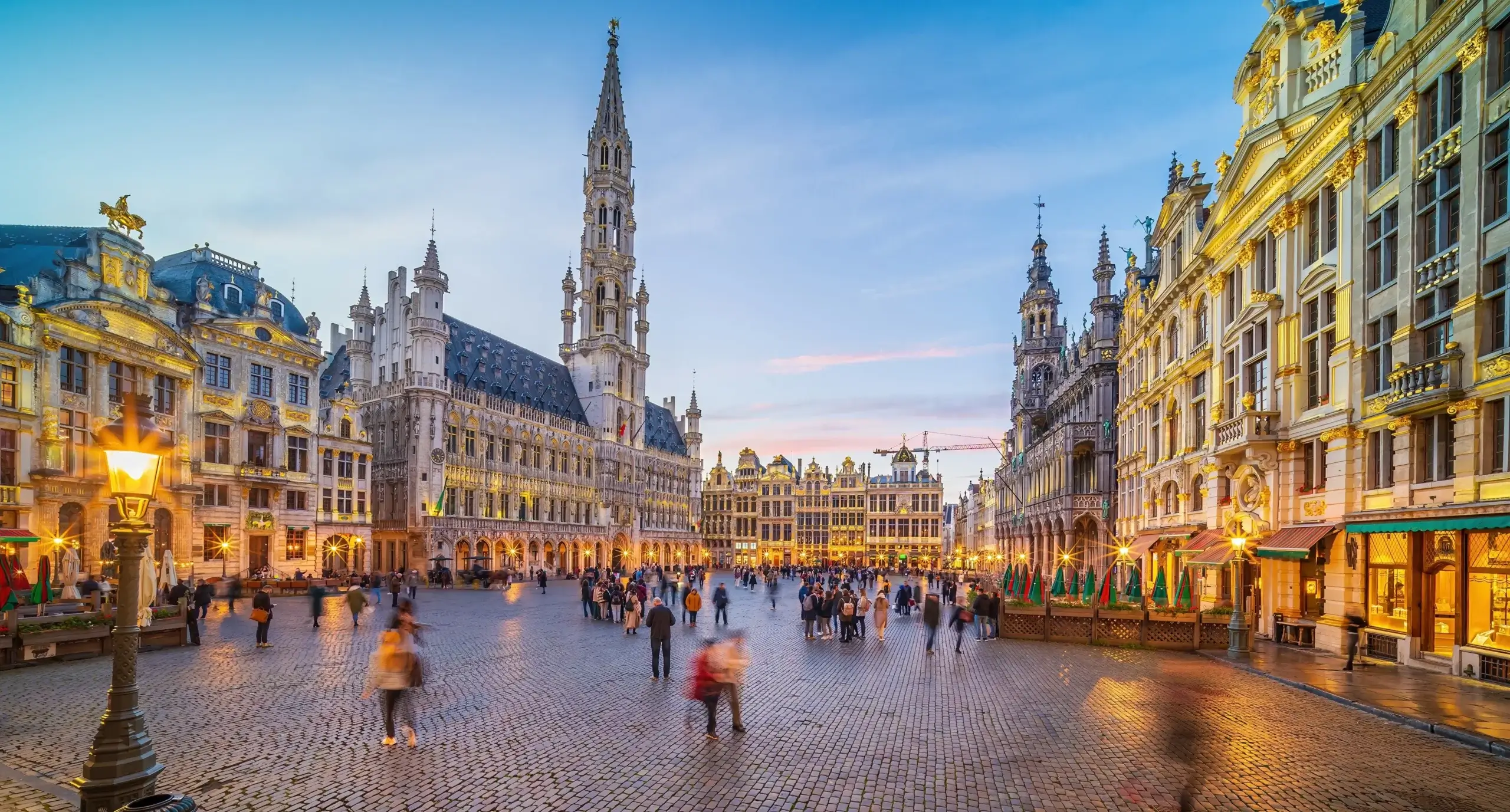 Grand Place i Bruxelles om aftenen med oplyste laugshuse og mennesker på torvet