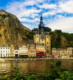 Kollegiatkirken Notre-Dame i Dinant ved floden Meuse med klippen og citadellet bagved
