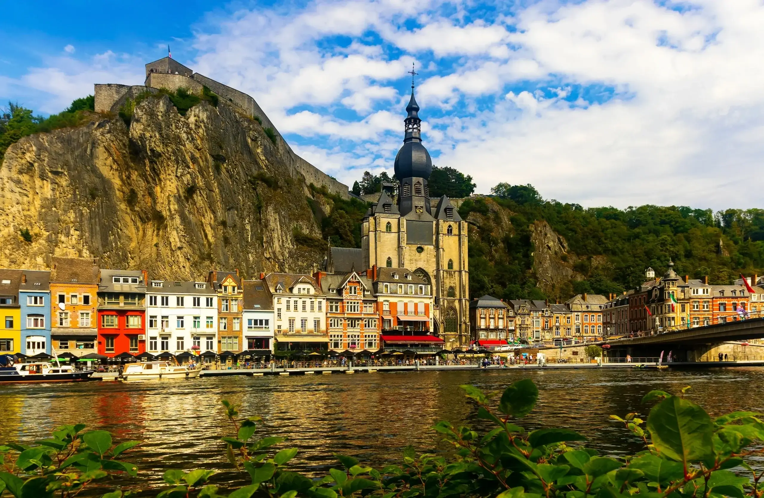 Kollegiatkirken Notre-Dame i Dinant ved floden Meuse med klippen og citadellet bagved