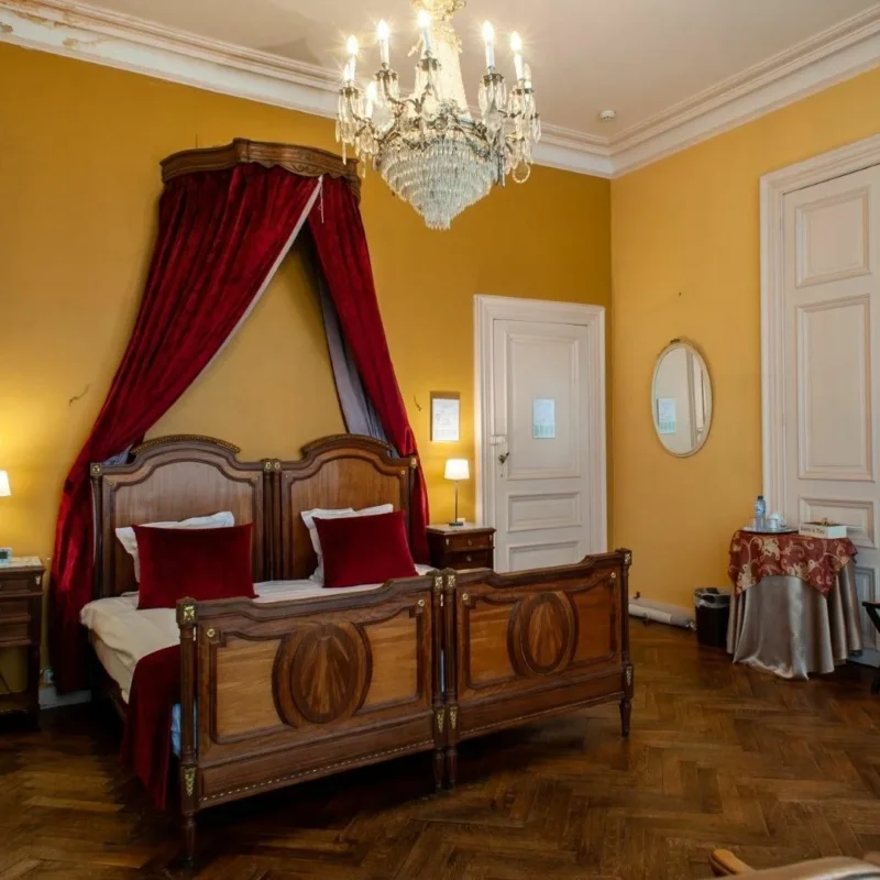 Værelse på Charme Hotel Hancelot i Gent med himmelseng, lysekrone og gule vægge