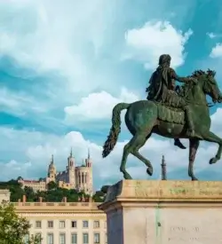 Rytterstatuen af Ludvig 14. på Place Bellecour i Lyon med basilikaen Notre-Dame de Fourvière på bakken bagved