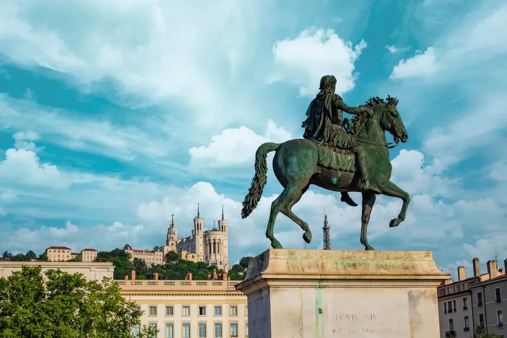 Rytterstatuen af Ludvig 14. på Place Bellecour i Lyon med basilikaen Notre-Dame de Fourvière på bakken bagved
