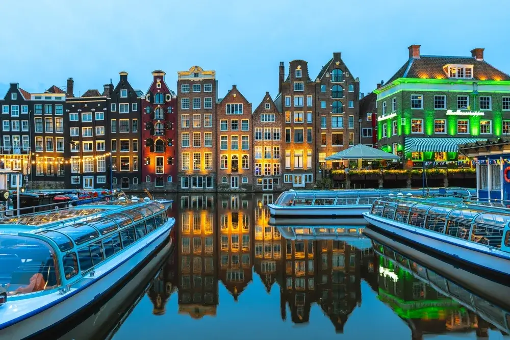 Smalle gavlhuse ved kanalen i Amsterdam spejler sig i vandet om aftenen