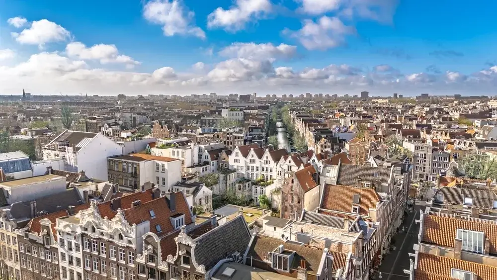 Udsigt over tagene og de gamle gavlhuse i Amsterdams centrum under en blå himmel