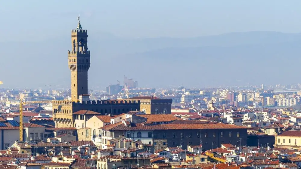 Palazzo Vecchios høje tårn rejser sig over Firenzes teglrøde tage med bakker i baggrunden