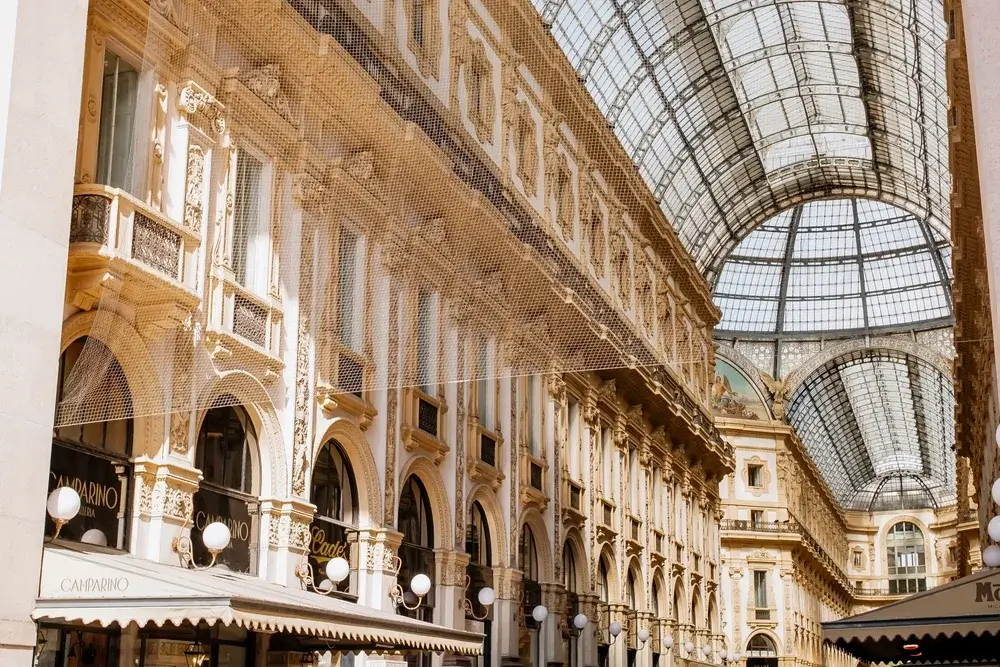 Glas- og jernloftet i Galleria Vittorio Emanuele II i Milano over udsmykkede facader med buer