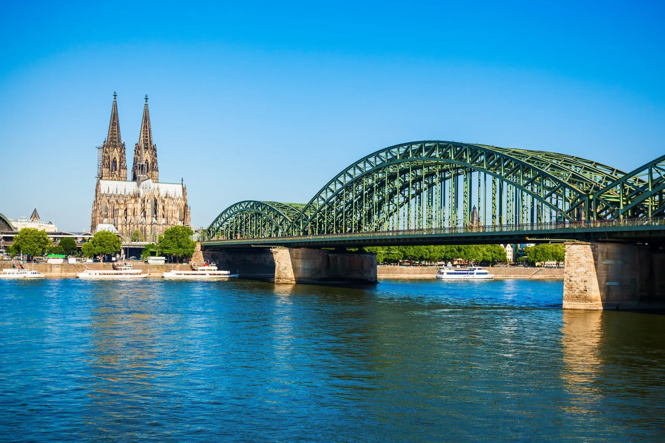 Kölner Dom set over Rhinen med Hohenzollernbroen i forgrunden