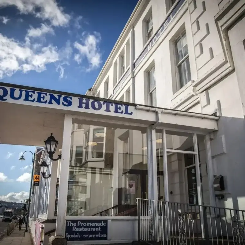 Facaden på The Queens Hotel med hotellets navn over indgangen