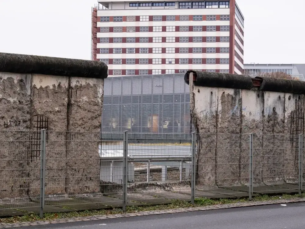 Bevarede betonsegmenter af Berlinmuren foran en høj bygning i Berlin