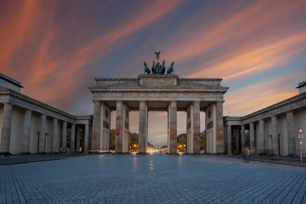 Brandenburger Tor i Berlin oplyst under en farvet aftenhimmel