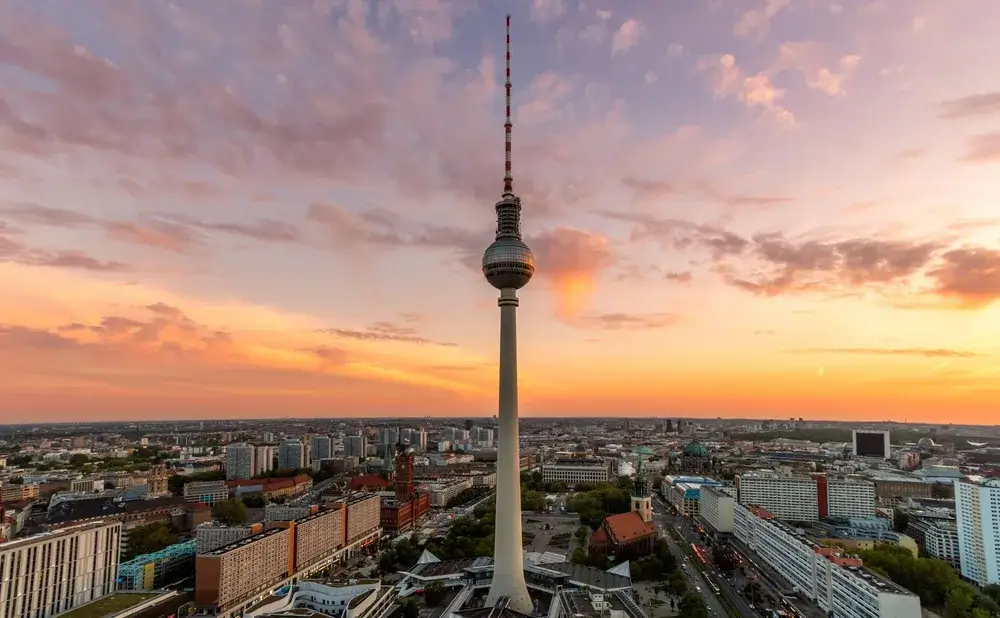 Berlins TV-tårn rejser sig over byens tage i solnedgangens orange lys