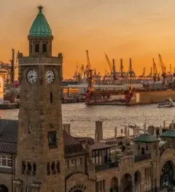 Tårnet ved Landungsbrücken i Hamborg med havnekraner og et krydstogtskib på Elben i solnedgang