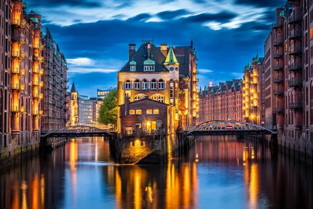 Wasserschloss mellem røde pakhuse i Speicherstadt i Hamborg, oplyst i blå time og spejlet i kanalen