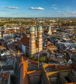 Frauenkirches to tårne med løgkupler over Münchens røde tegltage set fra luften