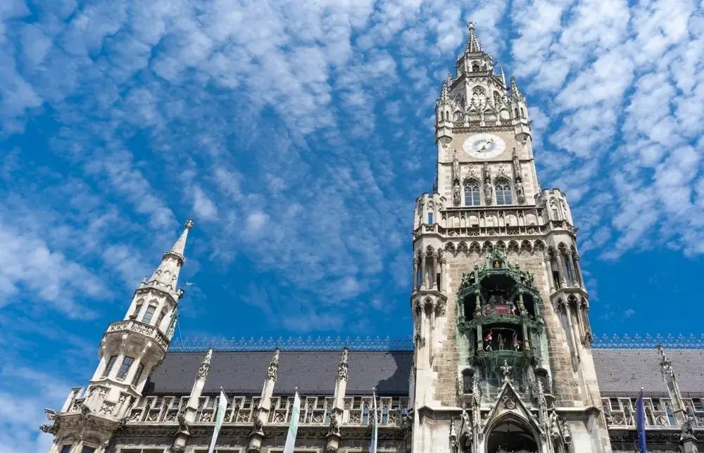 Det nygotiske rådhus Neues Rathaus i München med det høje urtårn mod en blå himmel med skyer