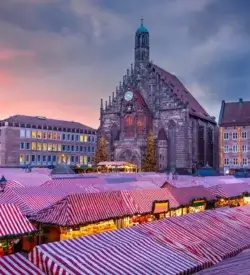 Julemarkedets boder med stribede tage på Hauptmarkt foran Frauenkirche i Nürnberg i skumringen