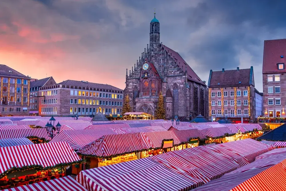 Julemarkedets boder med stribede tage på Hauptmarkt foran Frauenkirche i Nürnberg i skumringen