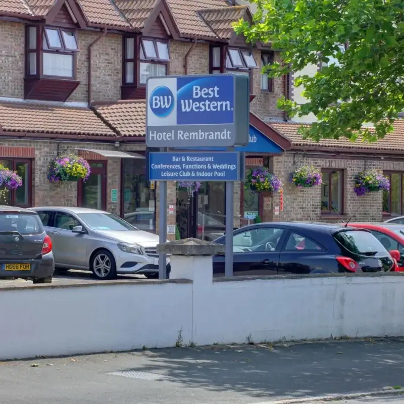 Hotellets facade med parkeringsplads foran