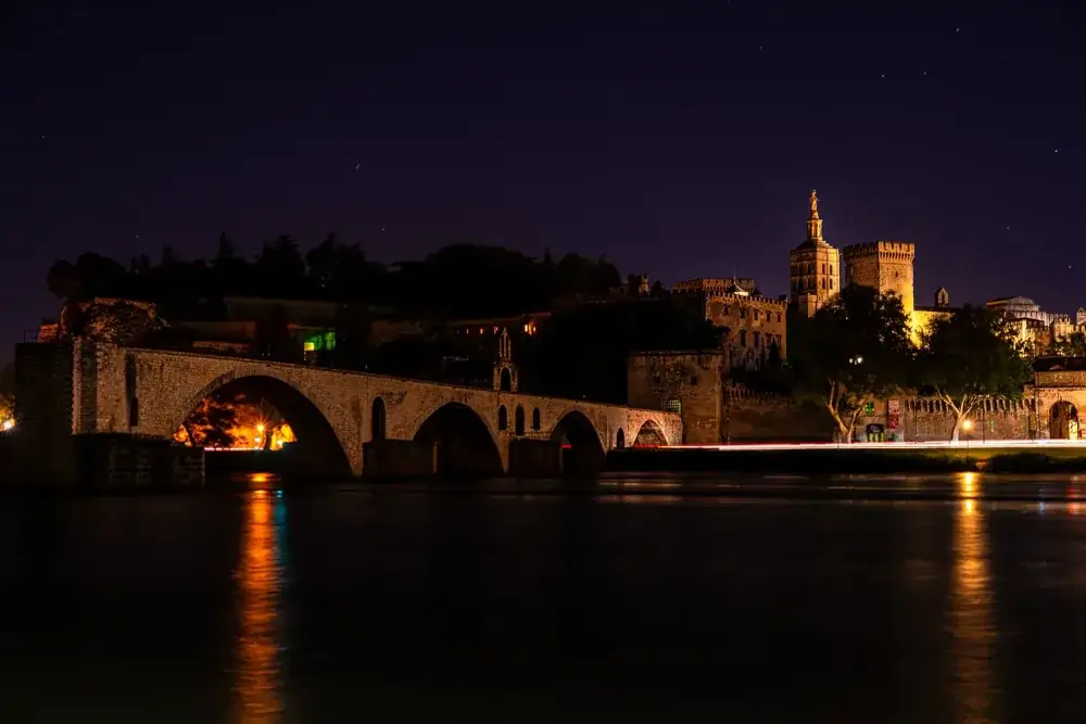 Broen Pont Saint-Bénézet og det oplyste pavepalads i Avignon om aftenen