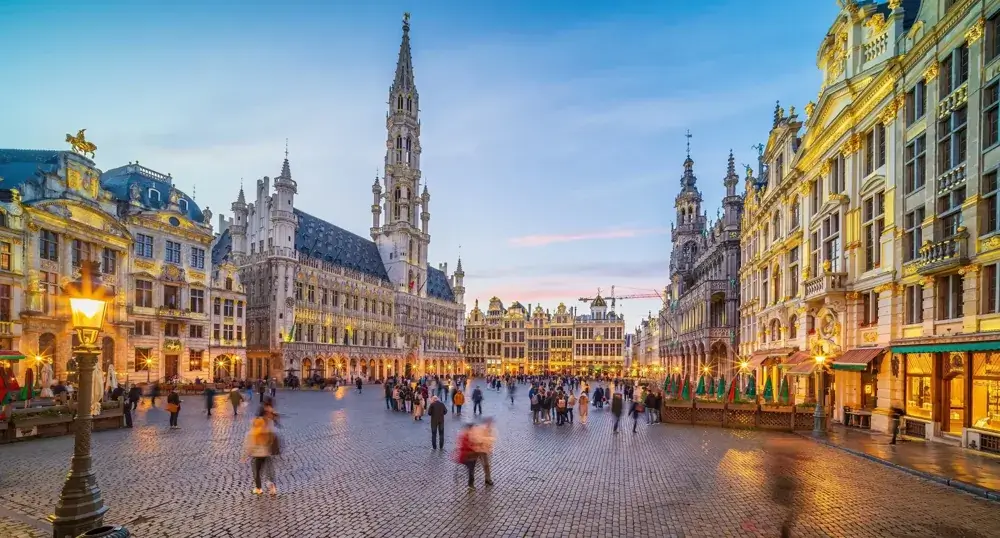 Grand Place i Bruxelles om aftenen med oplyste laugshuse og mennesker på torvet
