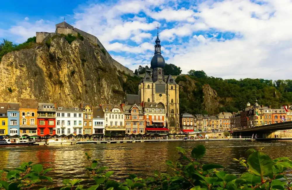 Kollegiatkirken Notre-Dame i Dinant ved floden Meuse med klippen og citadellet bagved
