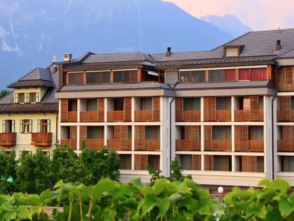 Facaden på Hotel Kompas i Bled med altaner og bjerge bagved