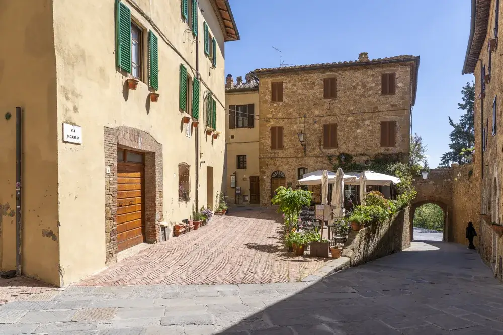 Stenhuse og en lille plads med café i den gamle by i Pienza