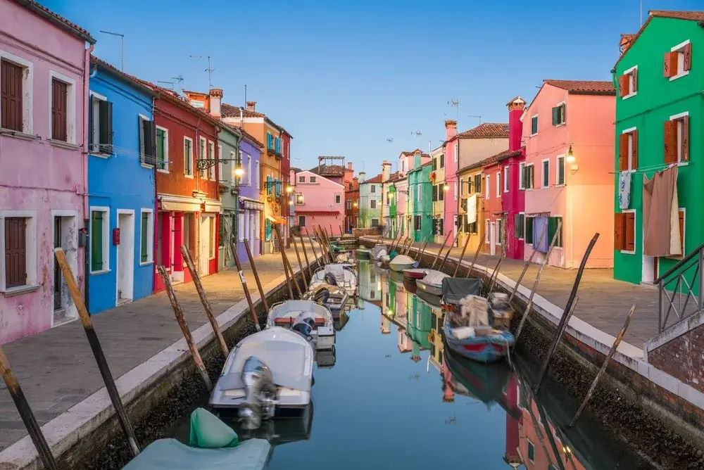 Kanal med små både mellem farverige huse på øen Burano ved Venedig