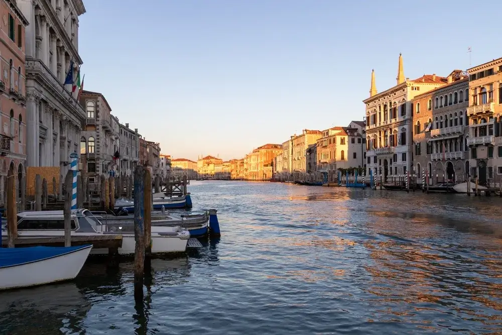 Canal Grande i Venedig i gyldent aftenlys med fortøjede både og historiske palæer langs vandet
