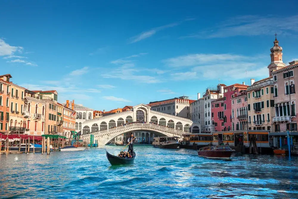 Rialtobroen over Canal Grande i Venedig med gondoler på vandet