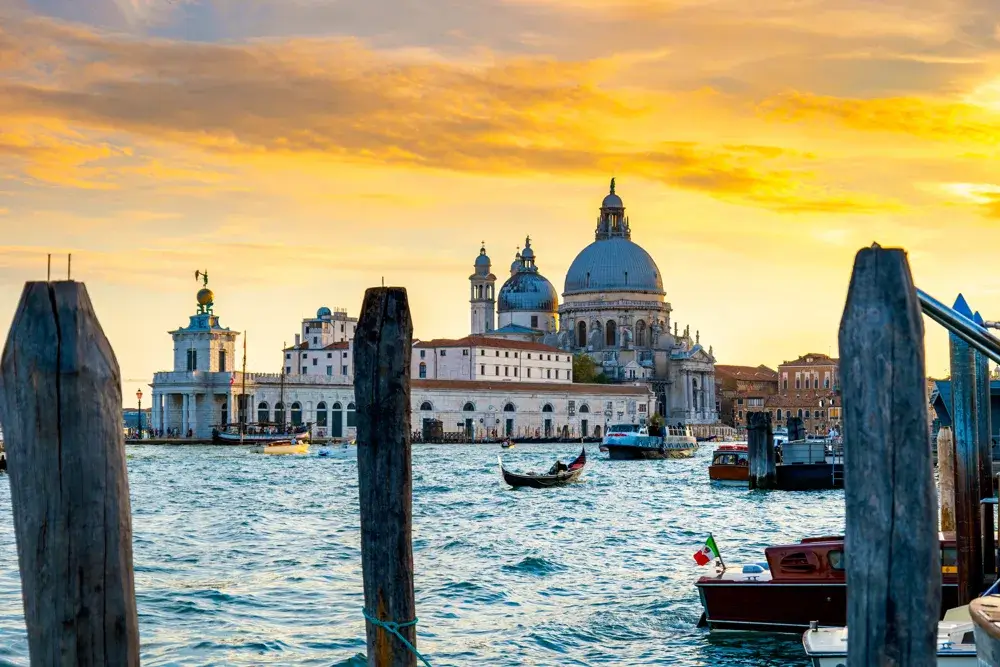 Kirken Santa Maria della Salute ved Canal Grande i solnedgang med en gondol på vandet