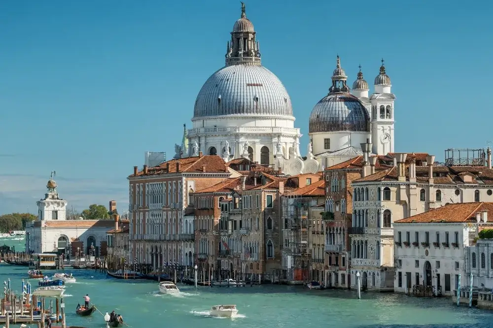 Basilikaen Santa Maria della Salute med hvide kupler over husene ved indløbet til Canal Grande i Venedig