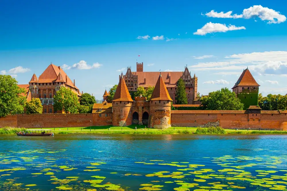Den røde teglstensborg i Malbork set over floden Nogat en sommerdag