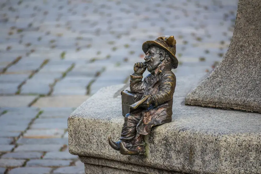 En lille bronzedværg sidder på en sten i Wrocław