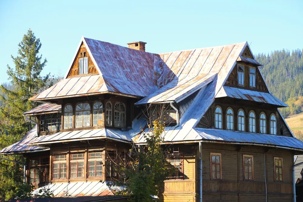 Traditionel trævilla i Zakopane-stil med stejlt tag og udskårne gavle mod blå himmel