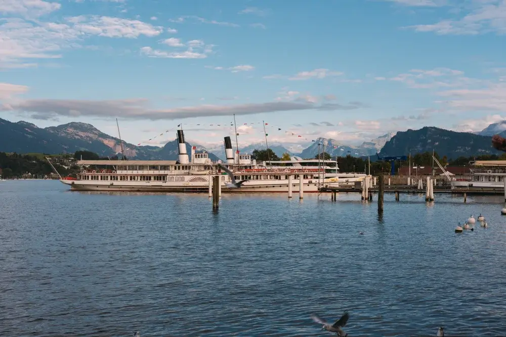 Hvide hjuldampere ved kajen i Luzern med Vierwaldstättersøen og alperne bagved