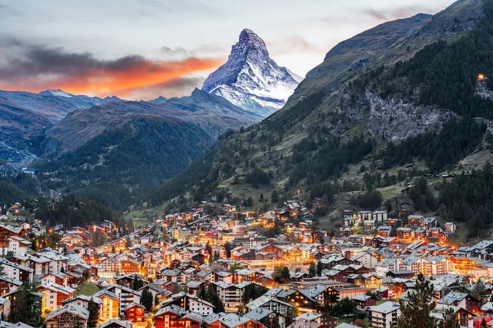 Matterhorn i rødligt aftenlys over de oplyste huse i Zermatt i dalen