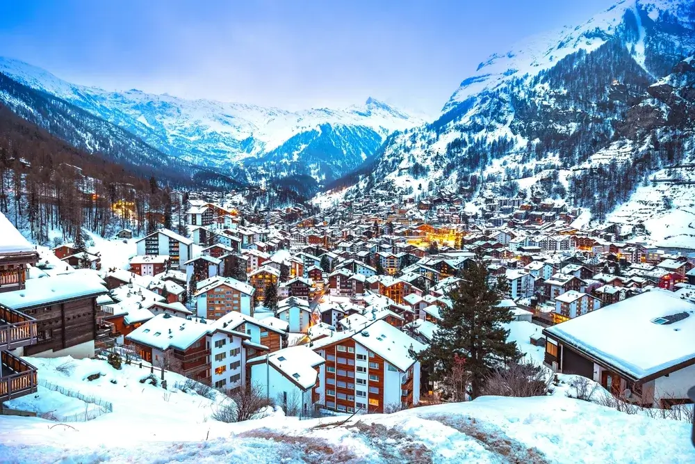 Snedækkede tage i bjerglandsbyen Zermatt omgivet af hvide alpetoppe
