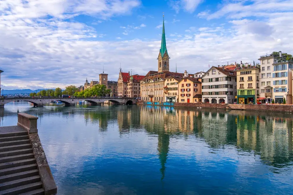 Zürichs gamle by med Fraumünster spejlet i Limmat en tidlig morgen