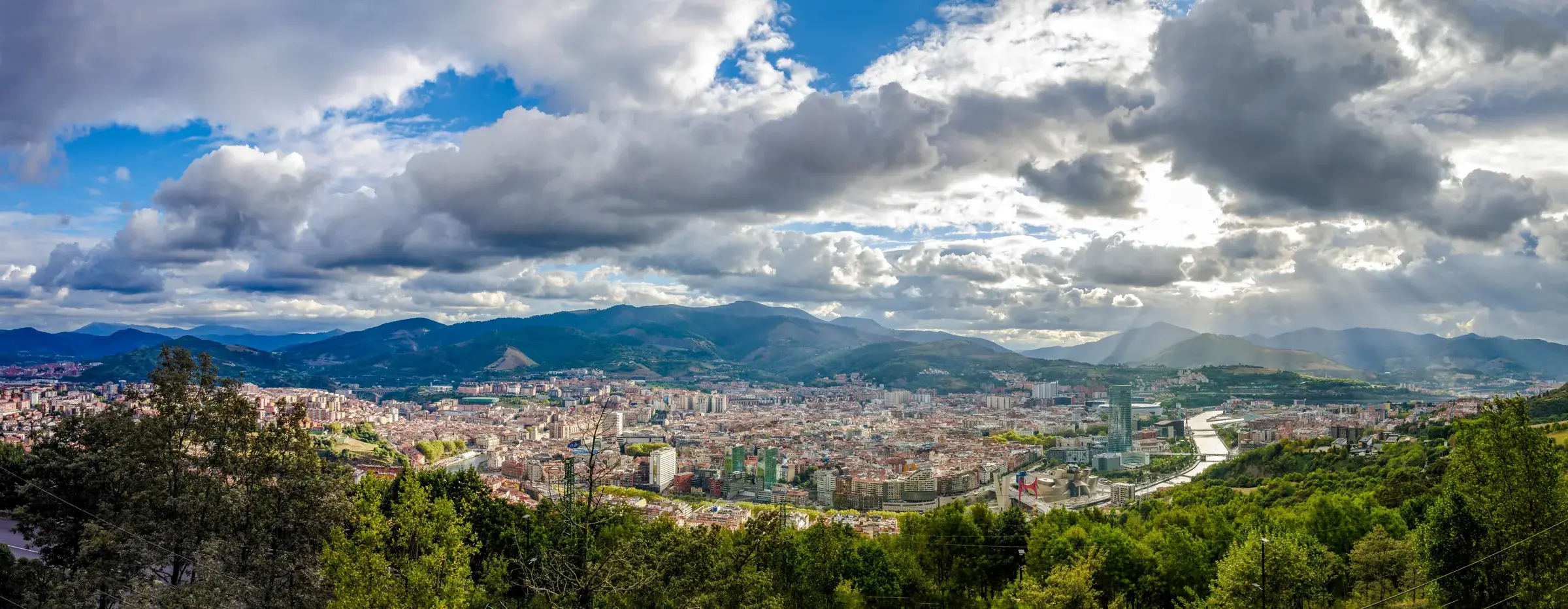 Panorama over Bilbao med floden og de grønne bjerge omkring byen