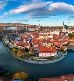 Den gamle by i Český Krumlov i en bue af floden Vltava med slottet og røde tage om efteråret
