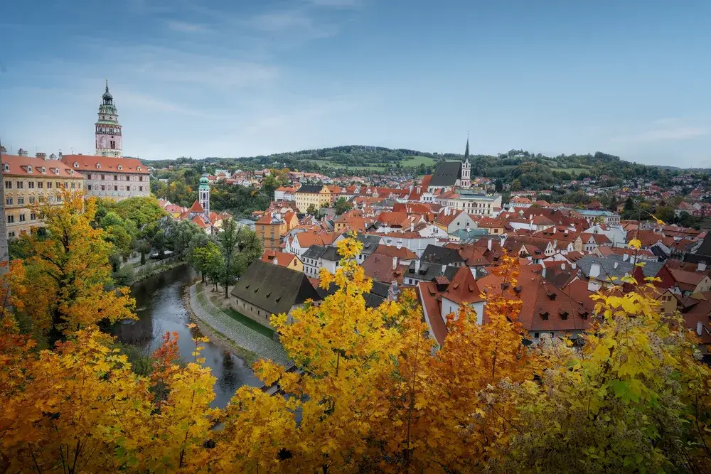 Luftfoto af Český Krumlov med slotstårnet, Sankt Vitus-kirken og efterårsfarvede træer