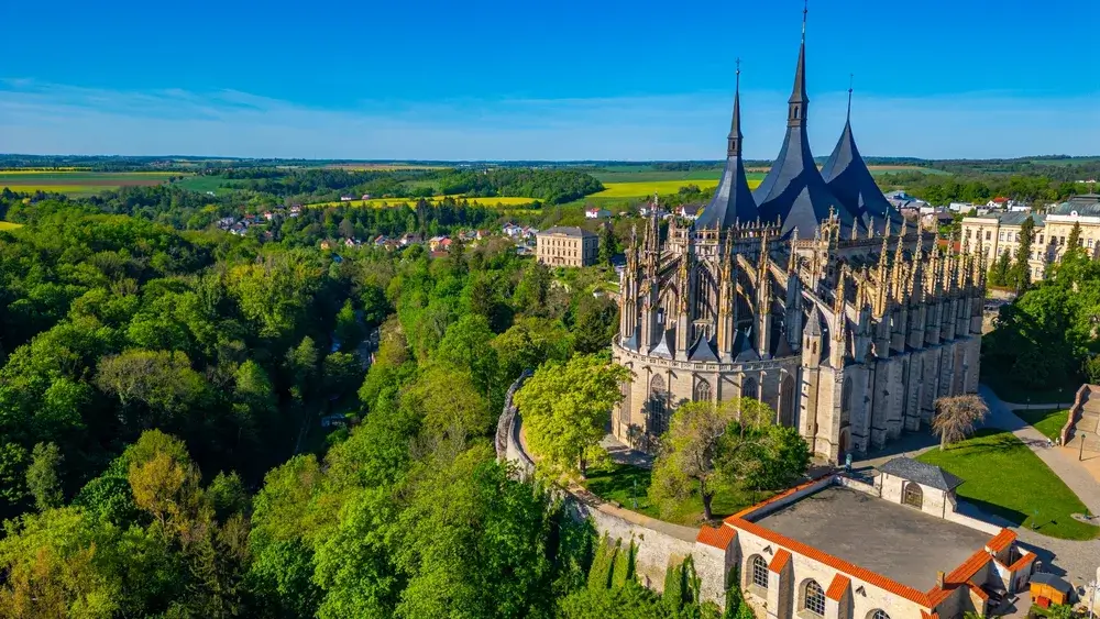 Den gotiske Sankt Barbara-kirke i Kutná Hora set fra luften med grønne skove og marker omkring