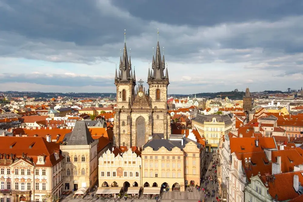 Luftfoto af Týn-kirkens gotiske tårne over Den Gamle Bydels Torv og de røde tage i Prag