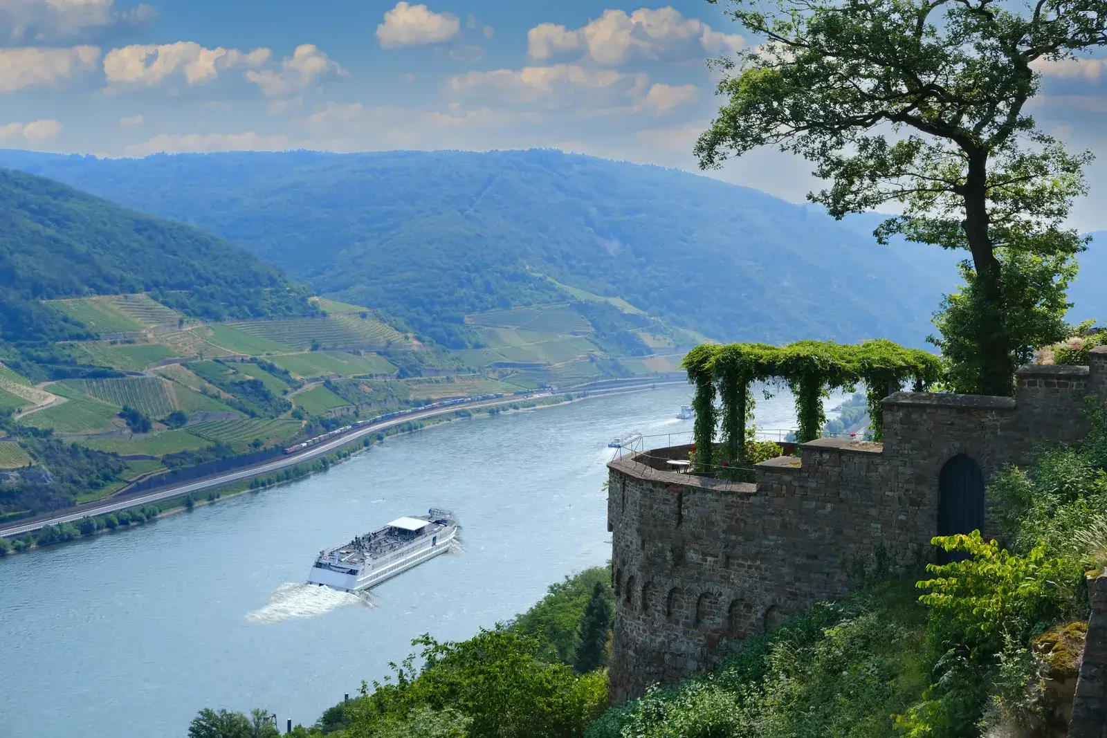 Udsigt fra Burg Sooneck over Rhinen med en hvid flodbåd og vinbjerge i dalen